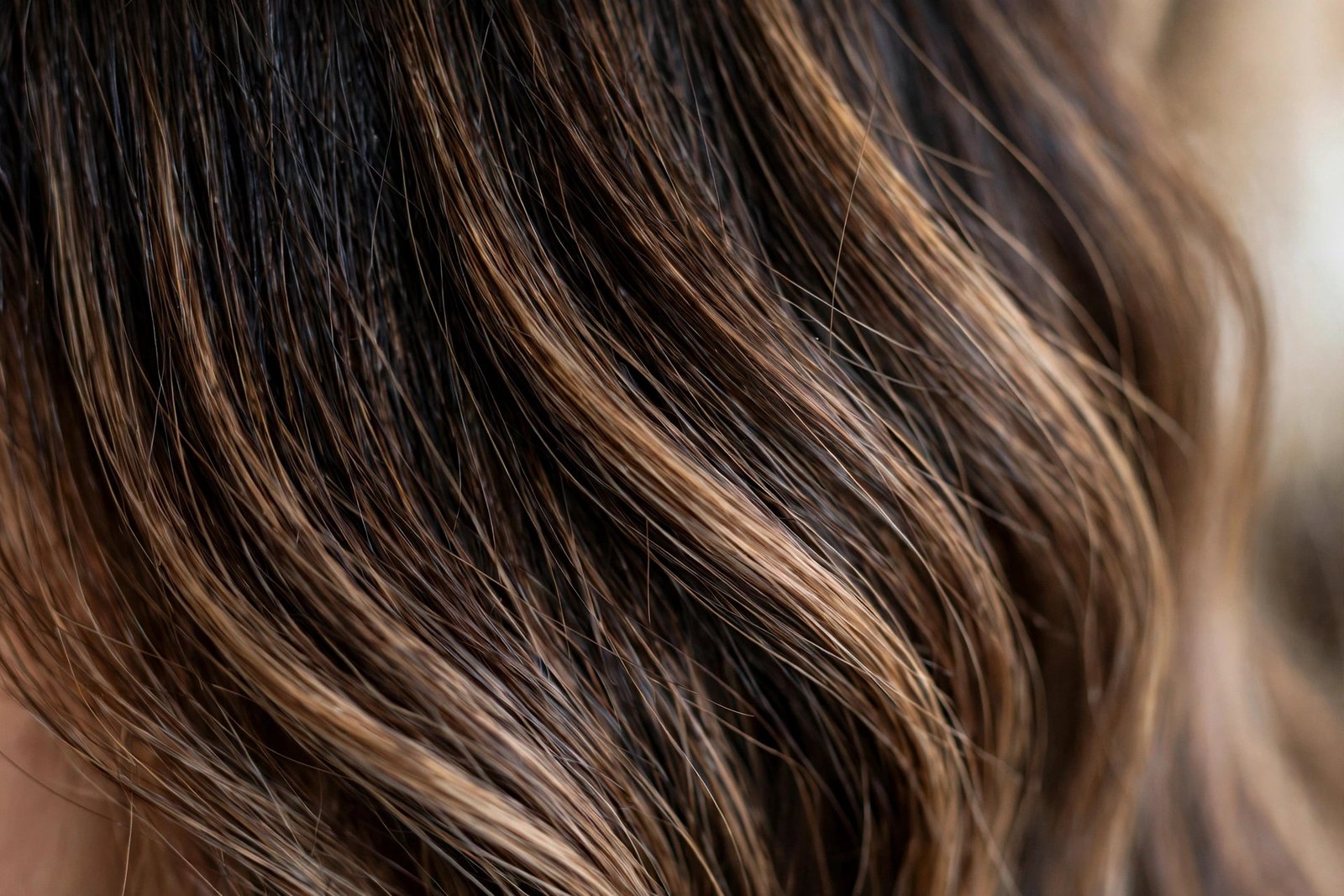 Close-up detail of hand-painted mocha balayage ribbons on brunette hair, dark espresso roots melting into caramel-mocha 