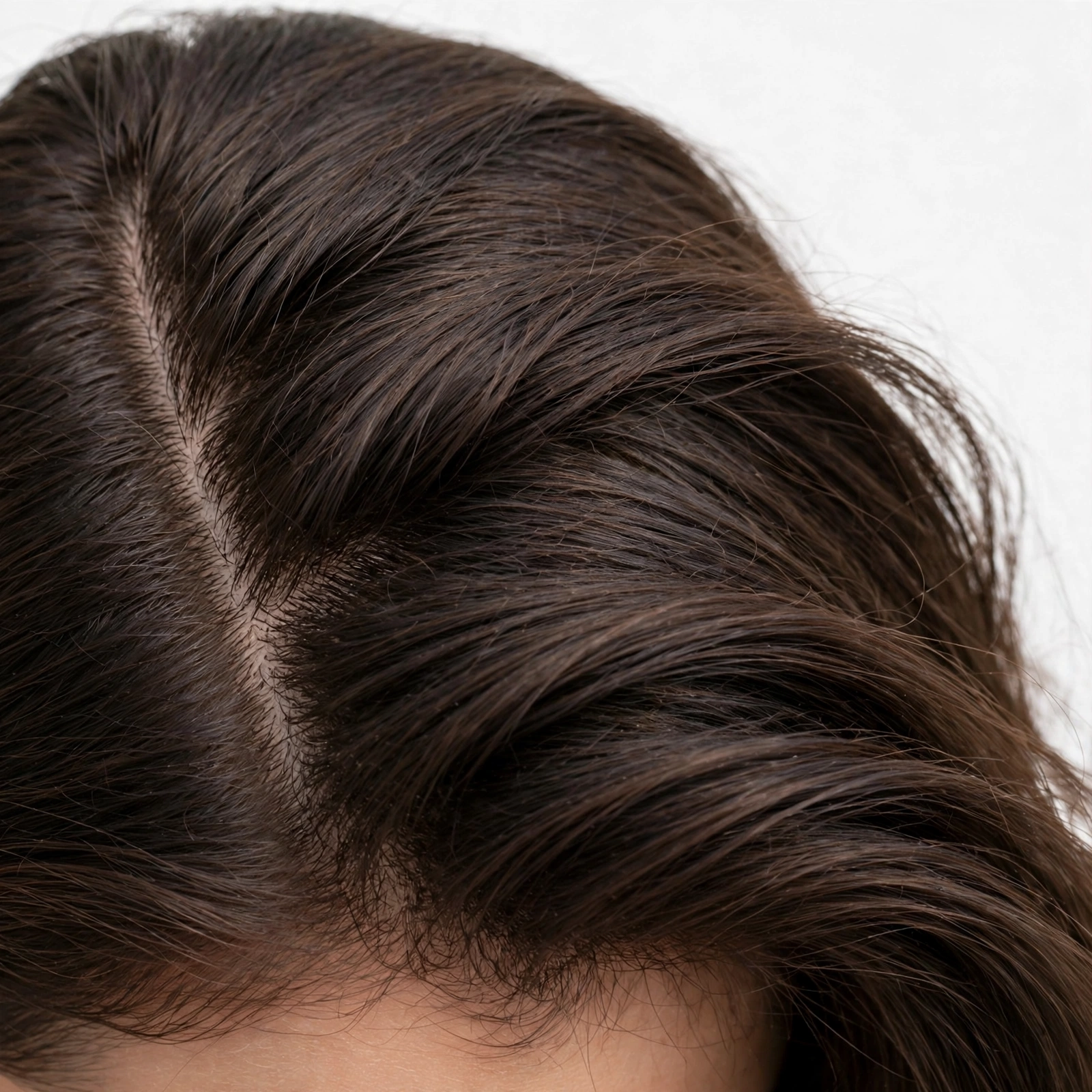 close-up detail of a woman's hair showing a crisp deep side part line at the scalp
